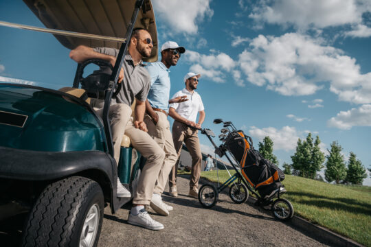 Group,Of,Smiling,Friends,Standing,Near,Golf,Cart,And,Looking