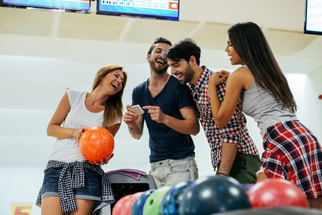 Cuatro amigos jugando a los bolos juntos.